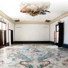 Interior de un museo de la seda con suelo de azulejos pintados y frescos en el techo.