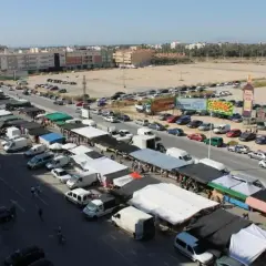Vista aérea de un bullicioso mercadillo en Elche, con puestos, furgonetas y coches aparcados.
