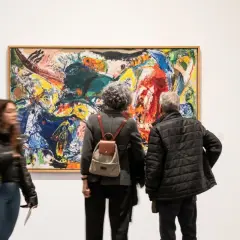 Personas observan una vibrante pintura abstracta en una de las exposiciones de Valencia.