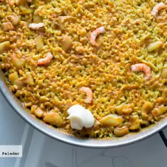 Un delicioso arroz a banda que lleva gambas y trozos de patata, servido en paellera con una cucharada de alioli.