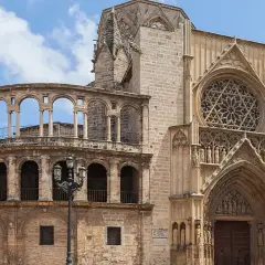 La **catedral de Valencia** luce su fachada gótica con un rosetón y un pórtico detallado, junto a una estructura de arcos semicirculares.