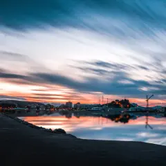 Atardecer en un puerto, con reflejos vibrantes en el agua. ¿Costa Blanca o Costa del Sol? La belleza es innegable.
