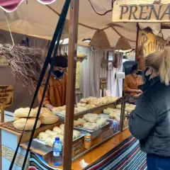 Puestos de pan y prenaos en el mercadillo Ruzafa. Una mujer con mochila roja compra.