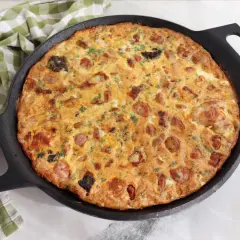 Arroz con costra de Elche recién hecho en sartén, con trozos de salchicha y perejil picado.