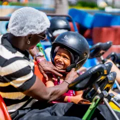 Un padre ajusta el casco a su hija en un kart en el Santa Pola Park. Ambos sonríen, listos para la carrera.