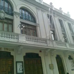 Fachada del **Teatre Tàlia**, un edificio blanco con grandes ventanales, balcones de hierro forjado y puertas de madera.