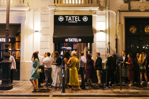 Gente elegante espera en la entrada de Tatel Valencia, un local nocturno iluminado.