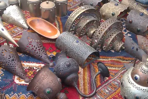 Lámparas y recipientes metálicos decorados, con un cuenco de madera, expuestos en un mercadillo de Polop.