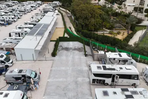 Amplio camper park en Alicante con numerosas autocaravanas y caravanas aparcadas, algunas con paneles solares.