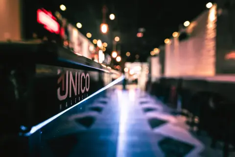 El logo "ÚNICO VALENCIA" brilla en la barra de un local, invitando a disfrutar del tardeo.