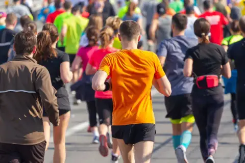 Corredores en la carrera 30k Sagunto, con un hombre de naranja en primer plano.