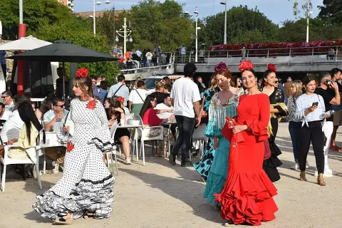 Mujeres con trajes de flamenca en la feria de abril de Valencia. Ambiente festivo con gente disfrutando.