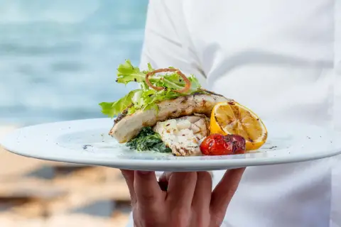 Delicioso plato de pescado a la parrilla con limón y tomate, servido en un restaurante en Cala Moraig.