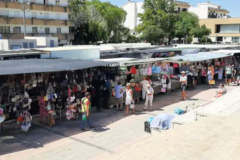 Gente paseando y comprando en el mercadillo de Jávea, con puestos de bolsos y ropa bajo toldos.
