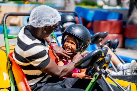 Un padre ajusta el casco a su hija en un kart en el Santa Pola Park. Ambos sonríen, listos para la carrera.