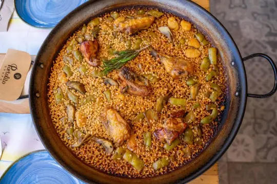 Paella valenciana, un clásico de qué comer en Valencia. Arroz con pollo, judías verdes y alcachofas en una paellera.