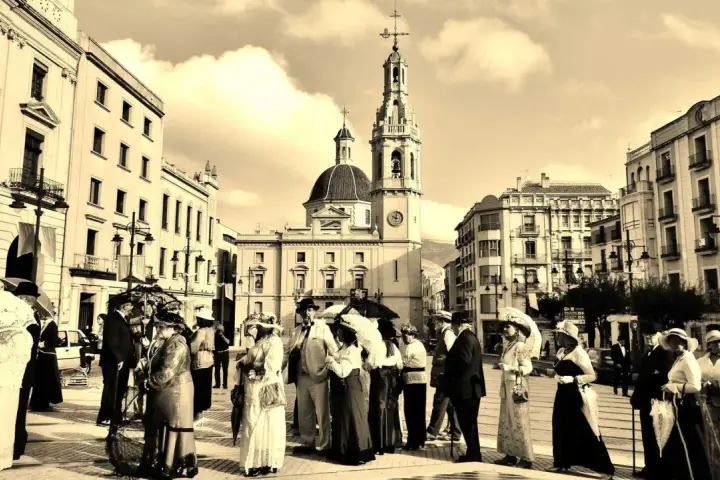 Gente vestida de época pasea por la plaza durante la Fira Modernista d'Alcoi.