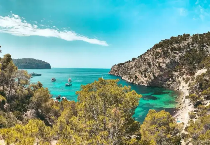 Unas calas de ensueño en la Costa Blanca, con aguas turquesas, vegetación exuberante y barcos navegando.