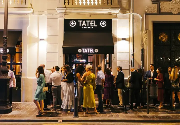 Gente elegante espera en la entrada de Tatel Valencia, un local nocturno iluminado.