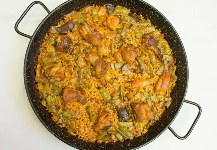 Paella mixta recién hecha, con pollo, judías verdes y arroz dorado. Un delicioso paella rezept para compartir.