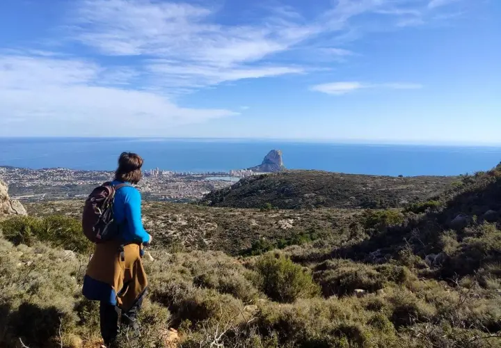 Senderista contempla el Peñón de Ifach y la costa desde una de las rutas de Calpe.