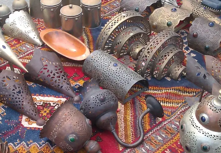 Lámparas y recipientes metálicos decorados, con un cuenco de madera, expuestos en un mercadillo de Polop.
