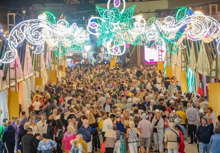 Multitudinaria feria nocturna con arcos de luces y puestos.