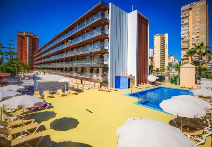 Terraza soleada con piscina y tumbonas en el hotel Diplomatic Benidorm. Edificio moderno con balcones y palmeras.