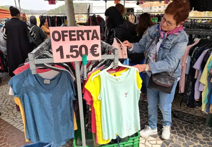 En el mercadillo de Gandía, una mujer busca ofertas. Ropa a 1,50€ en un puesto.