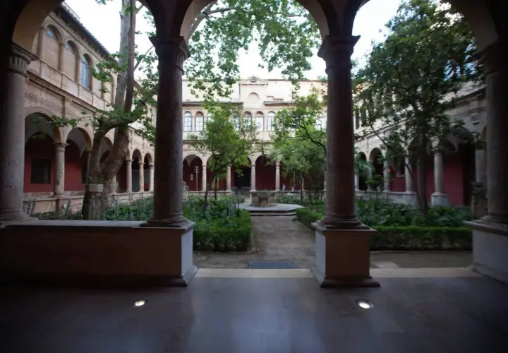 Patio interior con arcos y columnas en el barrio del Carmen, Valencia. Jardín frondoso con fuente central y árboles.