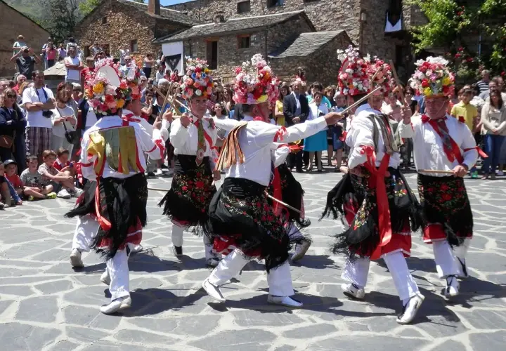 Hombres con trajes tradicionales y sombreros florales bailan en la plaza durante el **Día del Corpus**.