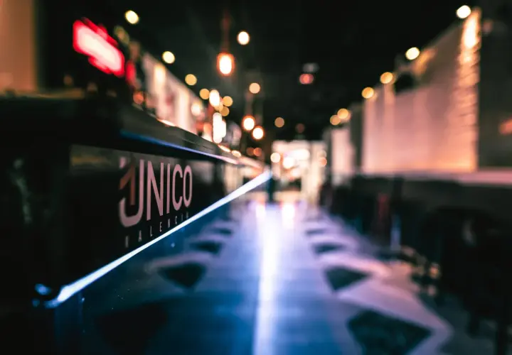El logo "ÚNICO VALENCIA" brilla en la barra de un local, invitando a disfrutar del tardeo.