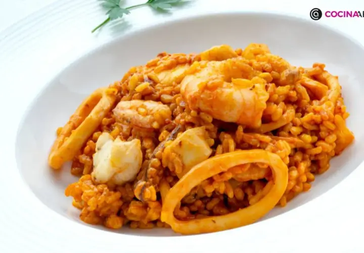 Arroz del senyoret con gambas, calamares y trozos de pescado blanco, servido en un plato blanco.