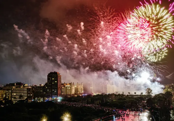 Espectacular noche de fuegos artificiales ilumina el cielo de Valencia. Multitudes observan la fiesta desde las calles.