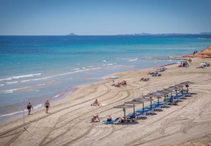 Una hermosa playa de mil palmeras con gente disfrutando del sol y el mar turquesa.