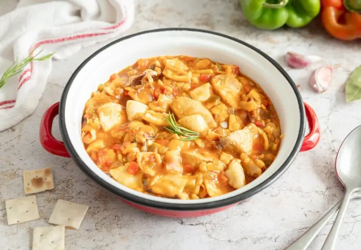 Gazpacho de mero Santa Pola, un plato marinero con trozos de pescado, pimientos y tomate en una cazuela roja.