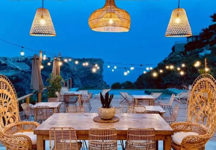 Un rincón de ensueño en el **dreamsea mediterranean camp**. Mesas de madera, sillas de ratán y luces cálidas bajo un cielo estrellado.