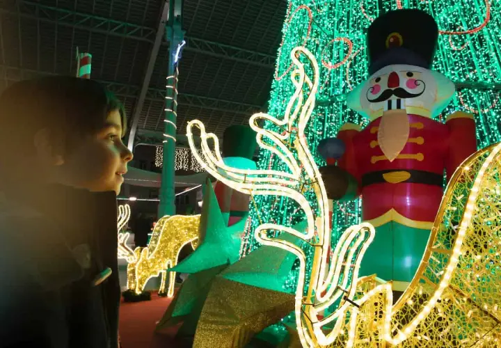Niño mira con asombro el encendido de luces de Navidad en Valencia, con un cascanueces gigante y renos luminosos.