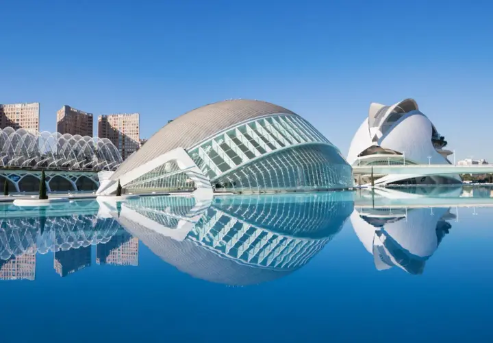 El Hemisfèric de Valencia, con su reflejo en el agua, se alza majestuoso bajo un cielo azul.