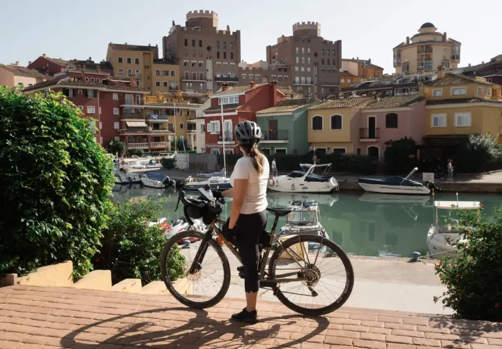 Ciclista en Valencia, disfrutando de las rutas ciclistas junto a un canal con casas coloridas y barcos.