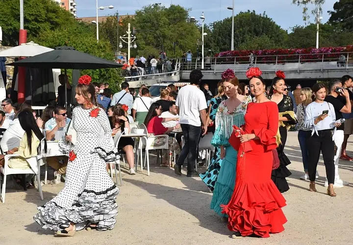 Mujeres con trajes de flamenca en la feria de abril de Valencia. Ambiente festivo con gente disfrutando.