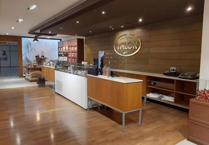 Interior de una tienda de chocolates Valor, con vitrinas, estanterías y el logo de la fábrica.