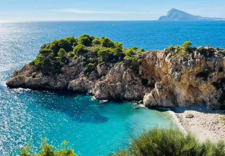 Una cala escondida con aguas turquesas y rocas escarpadas, un rincón idílico entre las mejores calas de Altea.