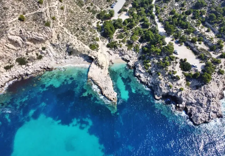 Vista aérea del racó del conill, una cala escondida con aguas cristalinas y rocas escarpadas.