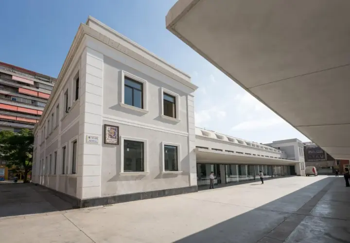 Edificio moderno y clásico en el **espacio Seneca Alicante**. Fachada gris, ventanas oscuras y un gran voladizo de hormigón.
