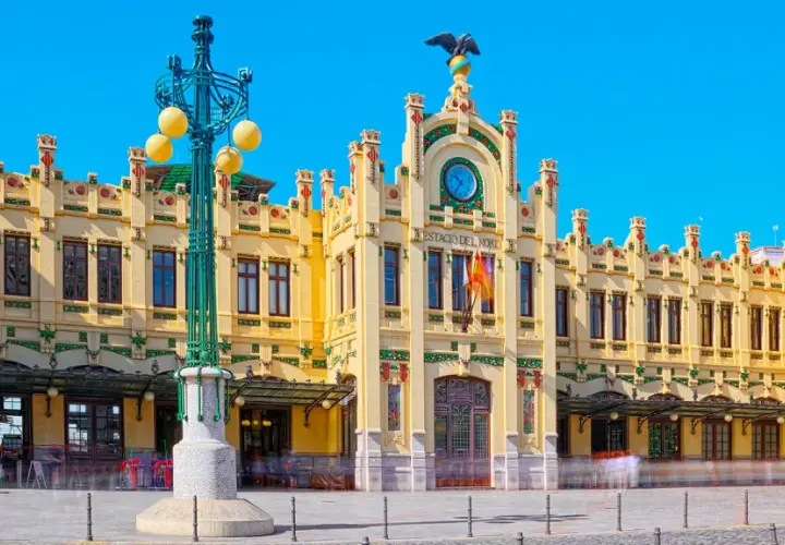 Estació del Nord Valencia, edificio modernista amarillo con detalles verdes y rojos, reloj y águila en la fachada.