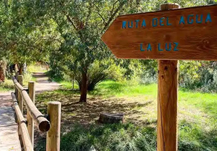 Cartel de madera indica "Ruta del Agua" y "La Luz" en Chelva. Camino de tierra con barandilla de madera.