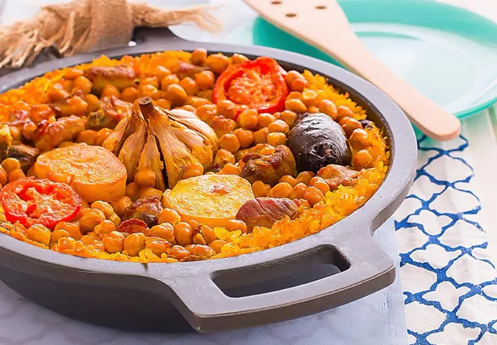 Delicioso arroz al horno con garbanzos, carne, tomate y una cabeza de ajo asada.