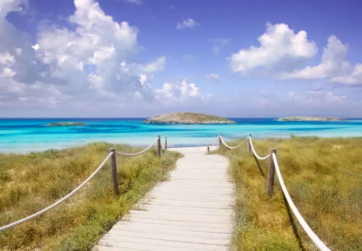 Camino de madera hacia las mejores playas del Levante. Aguas turquesas, arena blanca y un islote solitario.