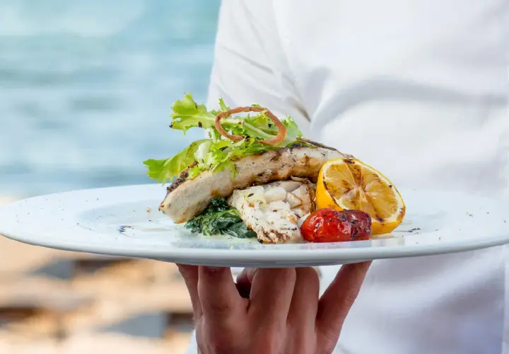 Delicioso plato de pescado a la parrilla con limón y tomate, servido en un restaurante en Cala Moraig.